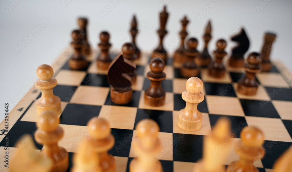 White and black wooden pieces on a chessboard. A chessboard set up during a game on a gray background. White and black wooden pieces on a chessboard. A chessboard set up during a game on a gray background.
