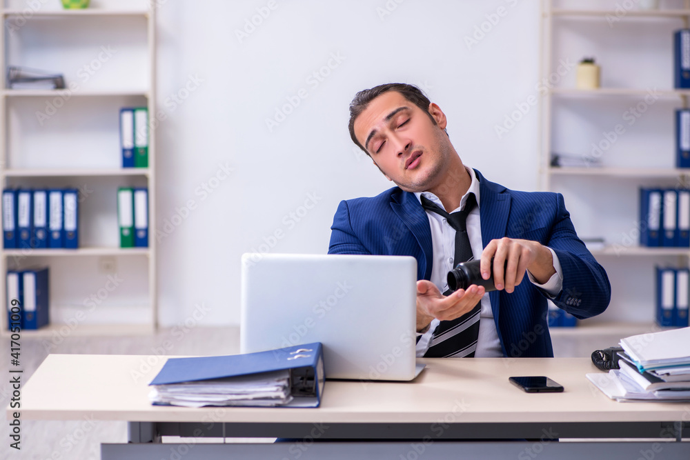 Sick male employee suffering at workplace Sick male employee suffering at workplace