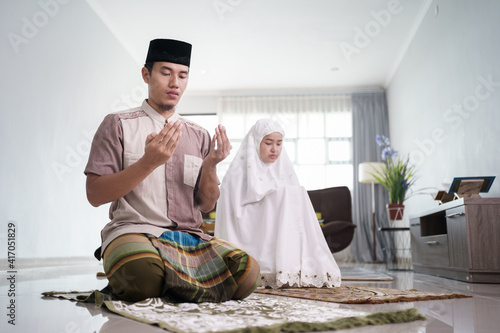 asian muslim husband and wife praying jamaah together at home photo