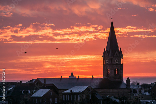 dramatic sunrise of the Baltimore skyline with a church steeple on the foreground.