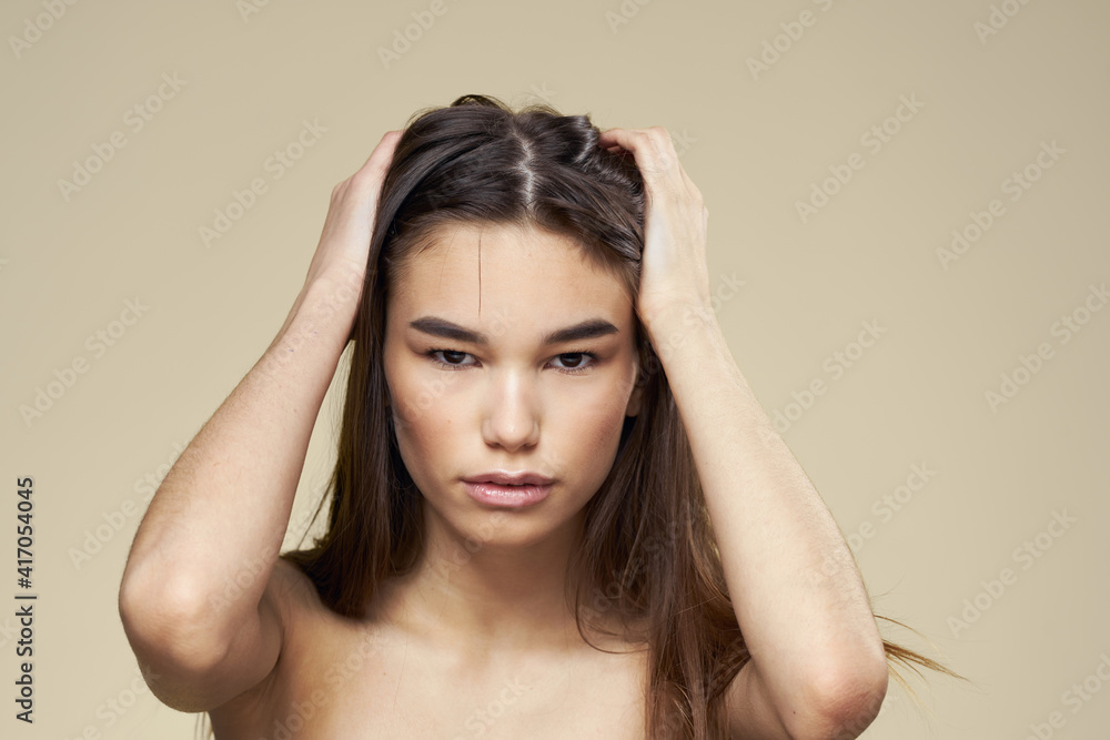 Fototapeta premium Pretty woman naked shoulders long hair body care beige background