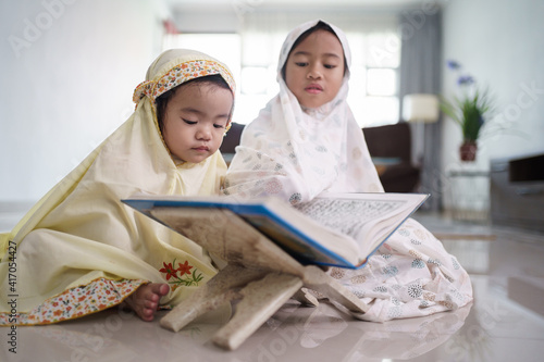 portrait of adorable muslim young kid read quran together at home photo