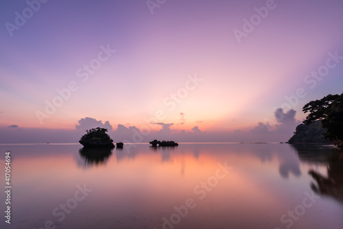 Beautiful and peaceful long exposure scene taken after suset at Hoshidate beach, with a calm sea, some islets and a beautiful colorful sky reflected on sea. Iriomote Island.