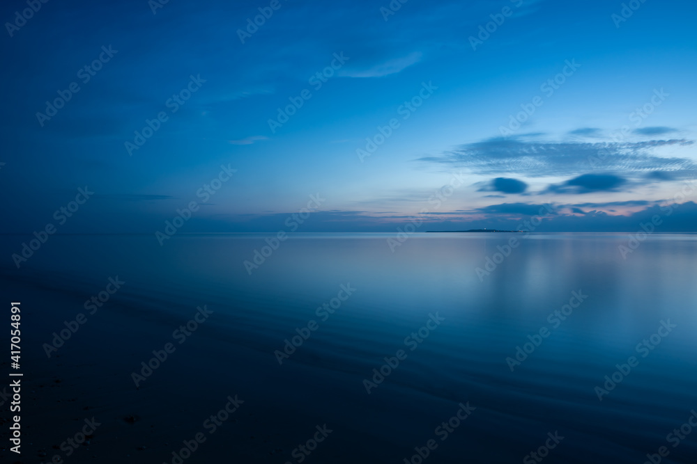Peaceful dawn in blue shades, smooth sea over wavy sands, island on horizon. Iriomote Island, natural world heritage.