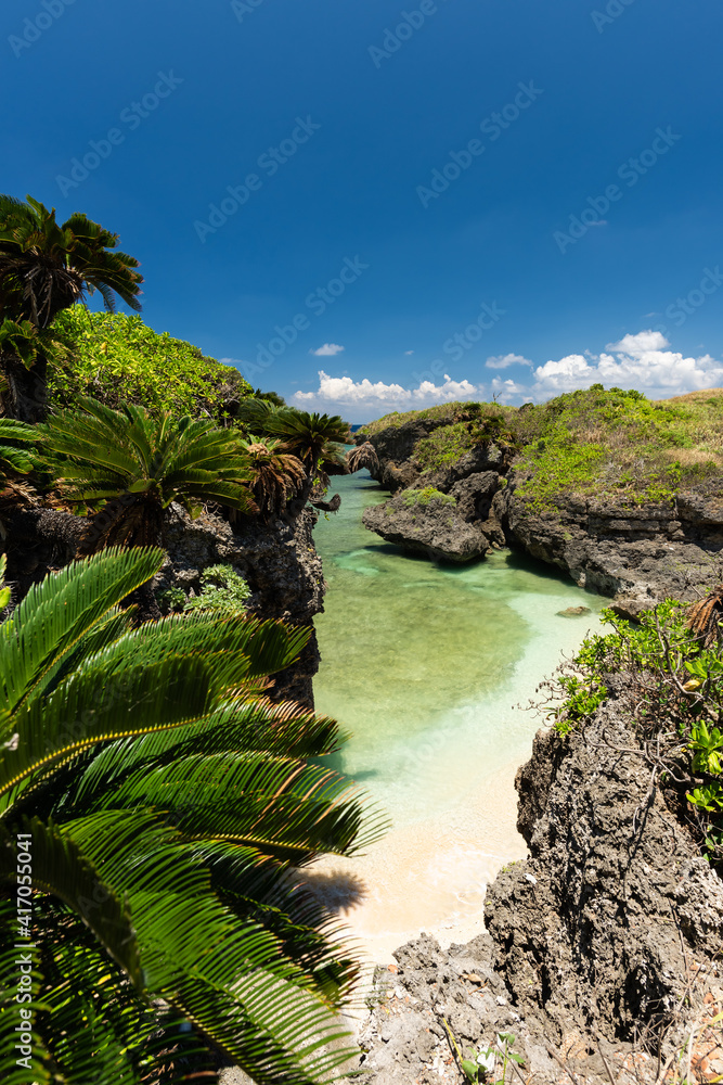 Beautiful little hidden beach with clear water, blue sky and rock formation typical of Okinawa in Unarizaki park seen from above.  Iriomote Island.