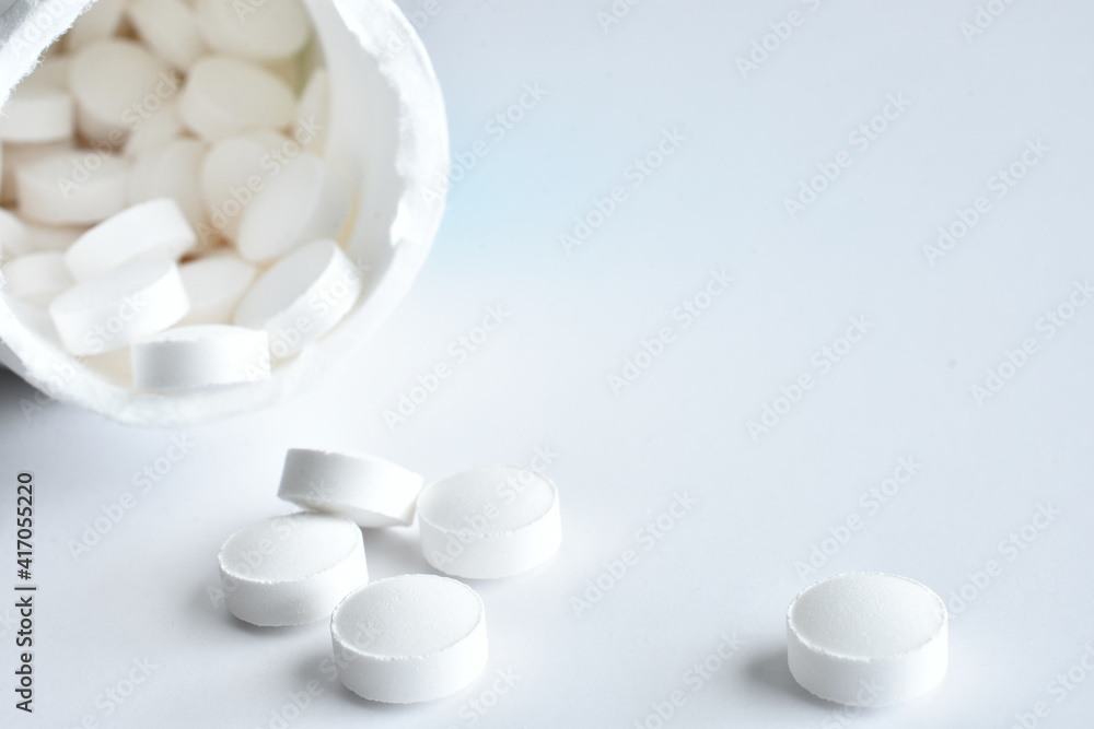 A close up image of several small white pills on a white background. A close up image of several small white pills on a white background.