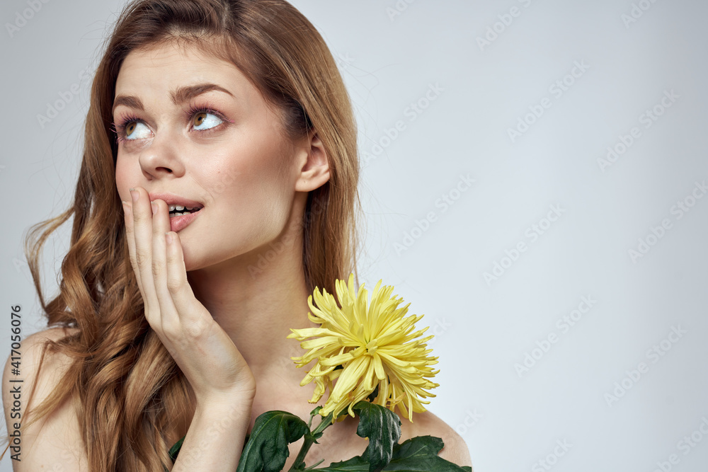 Portrait of a beautiful woman with a yellow flower on a light background charming smile model red hair Portrait of a beautiful woman with a yellow flower on a light background charming smile model red hair