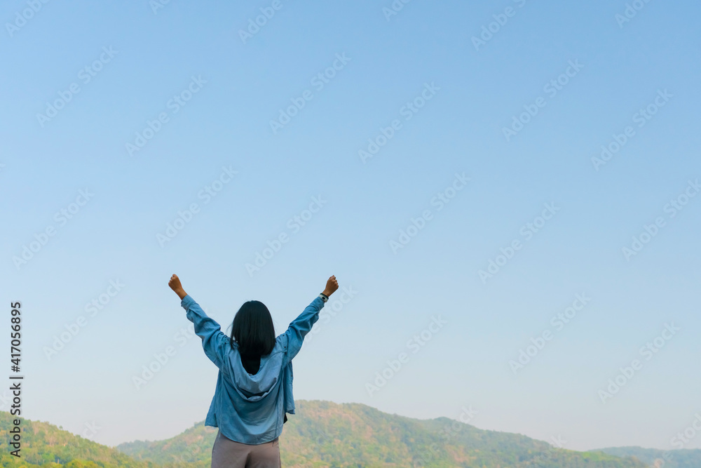 Woman rise hands up to sky freedom concept with blue sky and summer mountain background Woman rise hands up to sky freedom concept with blue sky and summer mountain background