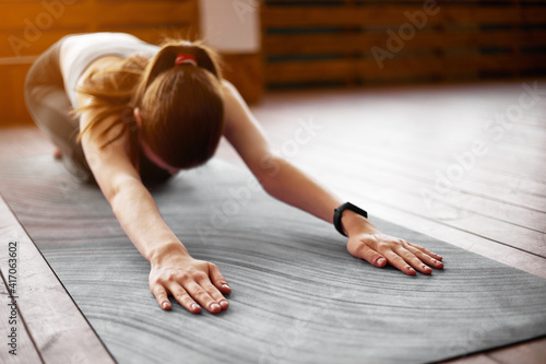 Young sporty attractive woman practicing yoga, doing Child exercise, Balasana pose