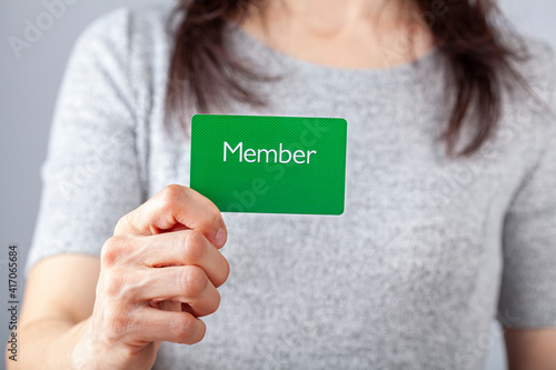 A young caucasian woman is holding a green card that says member on it. A customizable image which has space for text to be inserted. Being a member, membership dues, subscription, group concepts. photo