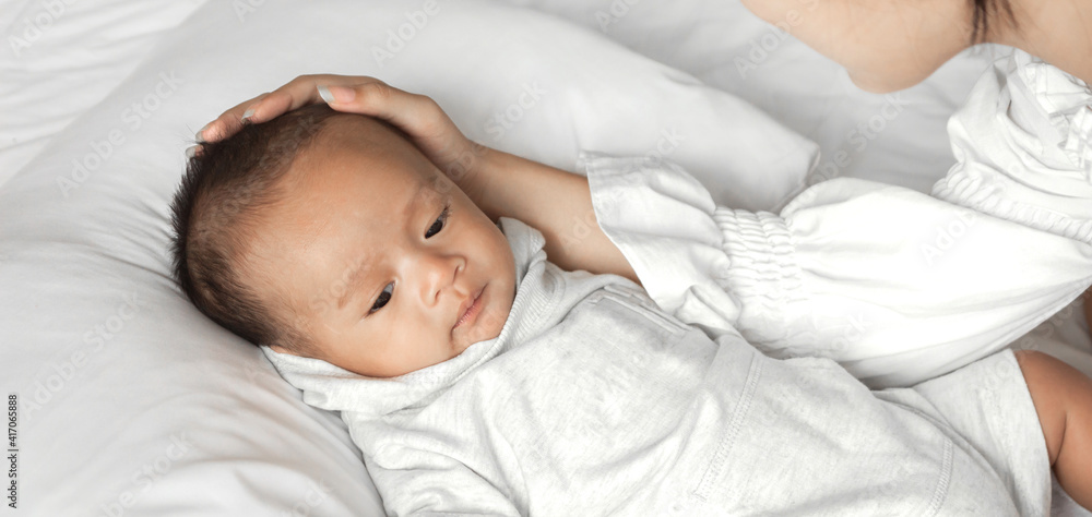 Portrait of enjoy happy love family asian mother playing with adorable little asian baby.Mom touching with cute son moments good time in a white bedroom.Love of family concept Portrait of enjoy happy love family asian mother playing with adorable little asian baby.Mom touching with cute son moments good time in a white bedroom.Love of family concept
