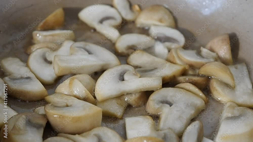 Sliced mushrooms champignons fried in oil in a frying pan. Close up. Sliced mushrooms champignons fried in oil in a frying pan. Close up.
