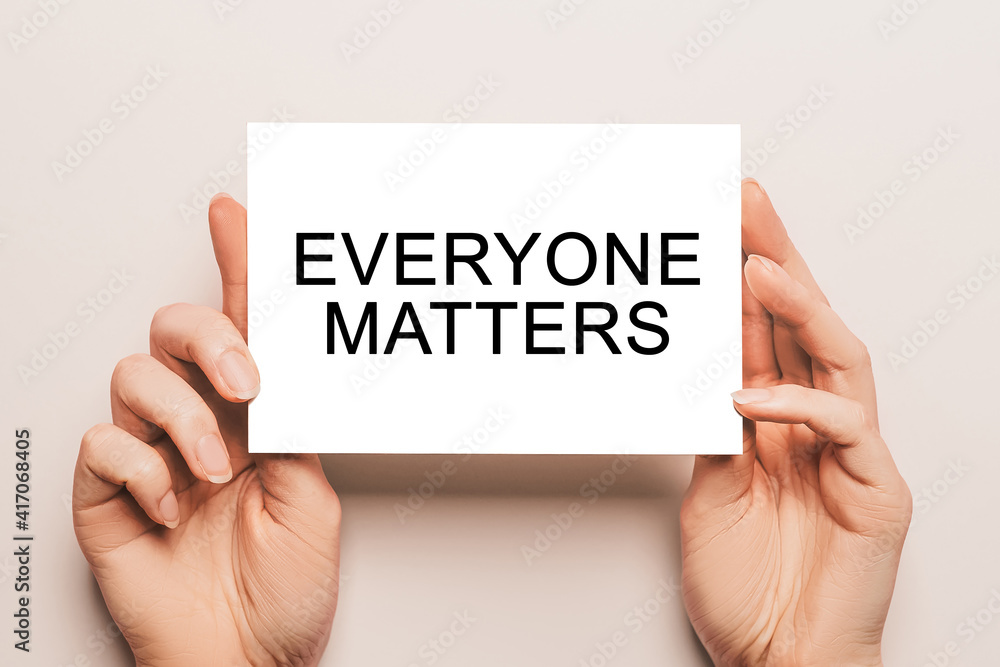 Female hands hold card paper with text Everyone Matters on a yellow background. Business and finance concept Female hands hold card paper with text Everyone Matters on a yellow background. Business and finance concept
