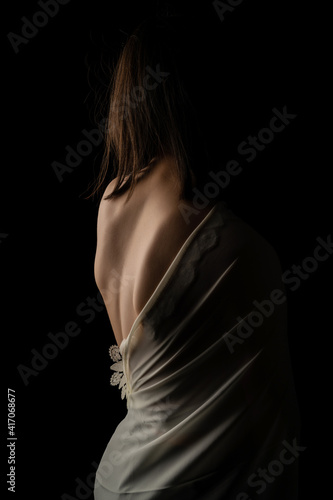 Back view of a beautiful half naked woman. Vertical shot, isolated black background.