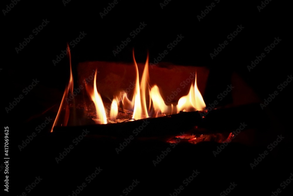 Naklejka premium a side view of yellow reddish flame coming out from firewood during night time.