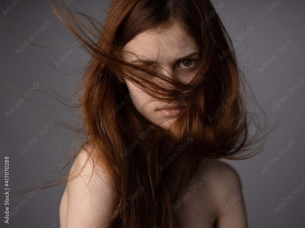 face of a red-haired woman on a gray background bare shoulders close-up model face of a red-haired woman on a gray background bare shoulders close-up model
