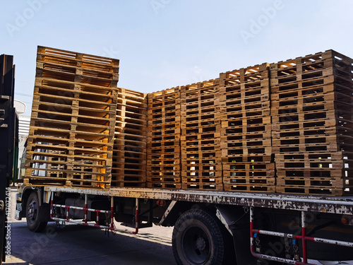 Worker driving forklift to loading and unloading wooden pallets from truck to warehouse cargo storage, shipment in logistics and transportation industrial, wood pallets stack