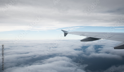 Plane wing in a flight and dramatic cloudscape white clouds over europe