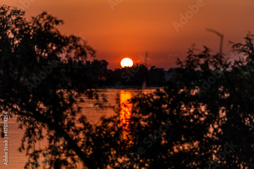 The sun hiding behind the horizon on Romantic Beach in Warsaw, Poland