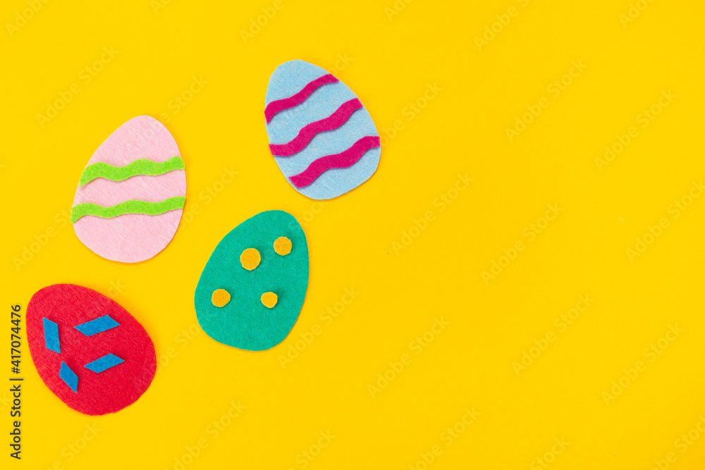 Easter decorations. Cut out of felt applications of colourful eggs on yellow background. Flat lay. Copy space Easter decorations. Cut out of felt applications of colourful eggs on yellow background. Flat lay. Copy space