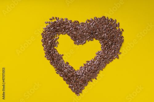 Flax seeds in the shape of a heart on a yellow background