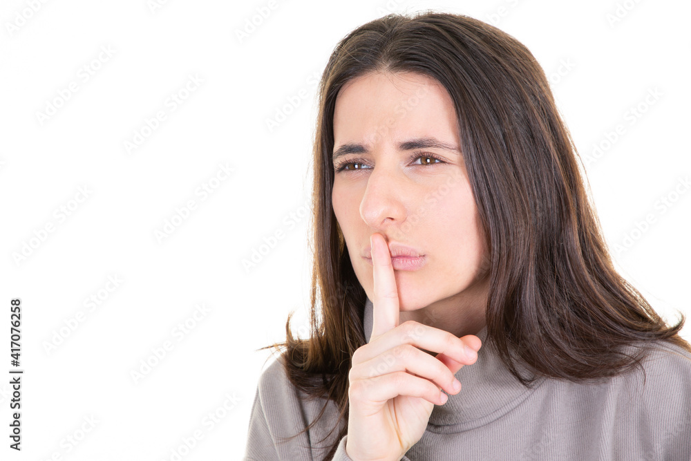 Cute mysterious girl showing silence shh sign holding forefinger on lips having secret isolated on white background Cute mysterious girl showing silence shh sign holding forefinger on lips having secret isolated on white background