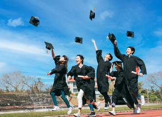 Happy Students with congratulations throwing graduation hats in the air for celebrating..