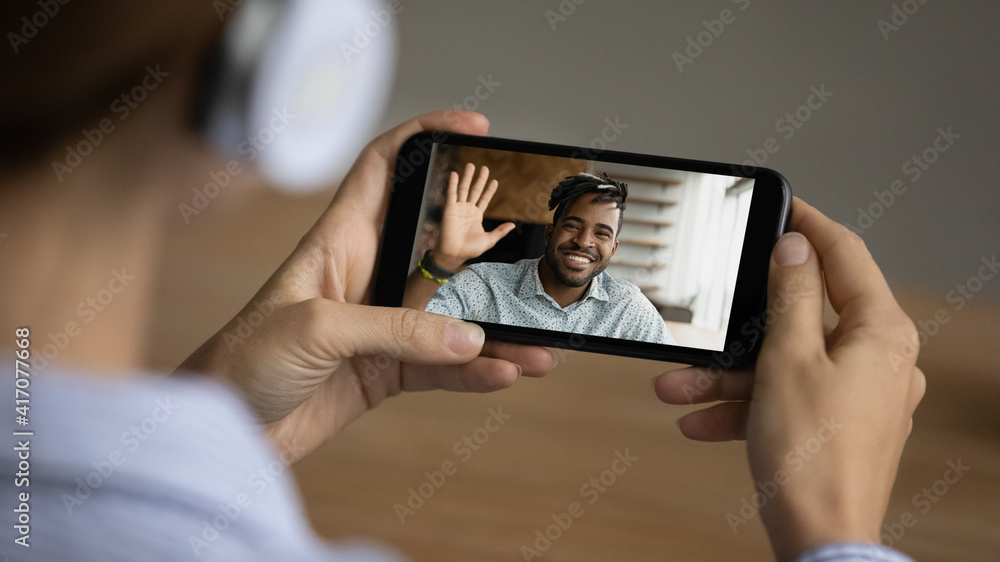 Close up of woman talk speak on video call on smartphone with smiling African American male colleague. Female have webcam online digital virtual conversation with ethnic friend. Technology concept.