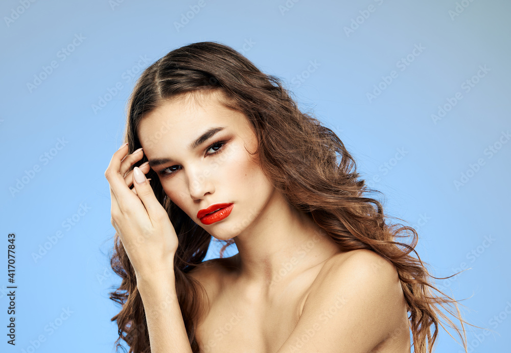 Female model curly hair brunette red lips shadows on the eyelids bared shoulders close-up Female model curly hair brunette red lips shadows on the eyelids bared shoulders close-up