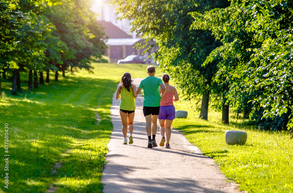 Obraz premium A man and girls go for a run in the city Park