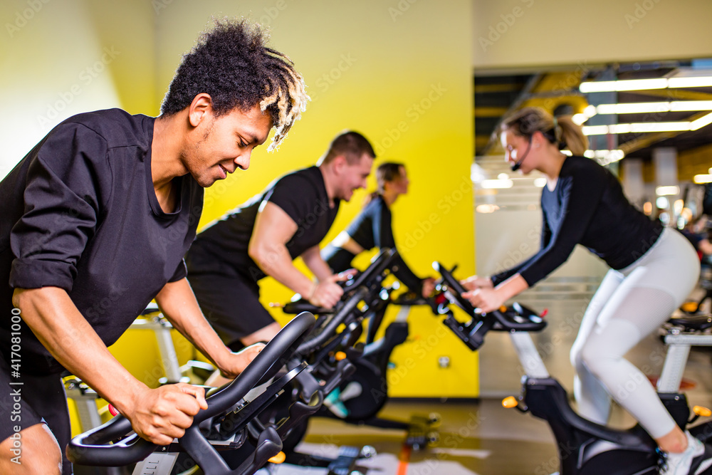 authentic mixed race group training on exercise bikes teamwork