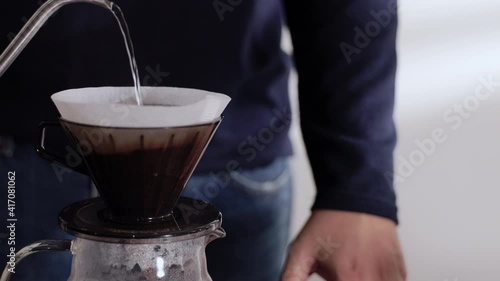 Coffee Drip Concept. Person Pouring Hot Water from Kettle into a Dripper. Making Pour Over Hot Coffee Drink in House. Zen and Cozy Living. Closeup shot