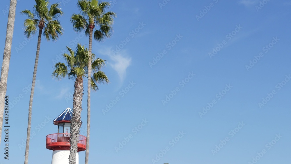 Retro lighthouse, tropical palm trees and blue sky. Red and white vintage old-fashioned beacon. Waterfront fisherman village near ocean sea harbor. Wharf or seaport, sunny summer in California USA.
