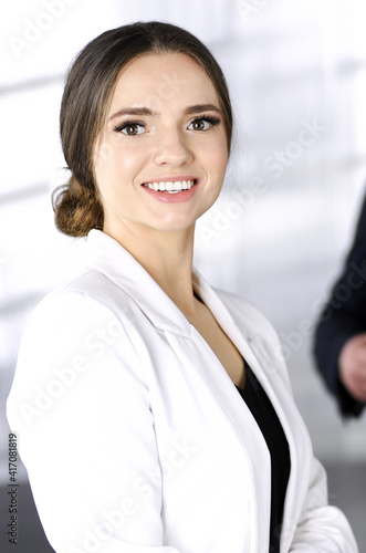 Portrait of a young successful businesswoman, while she is standing together with her colleague in a modern office. Concept of success in a business