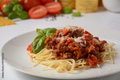 Traditional Italian spaghetti Bolognese served on a white plate with tomatoes and basil