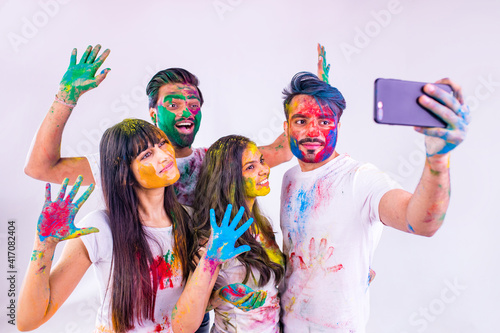 happy teenager friends with colour face and hair taking selfie photos on camera feeling good emotions together in white studio
