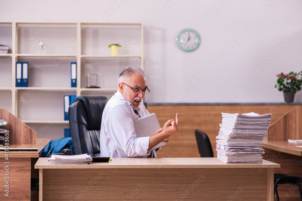Old male employee unhappy with excessive work in the office Old male employee unhappy with excessive work in the office
