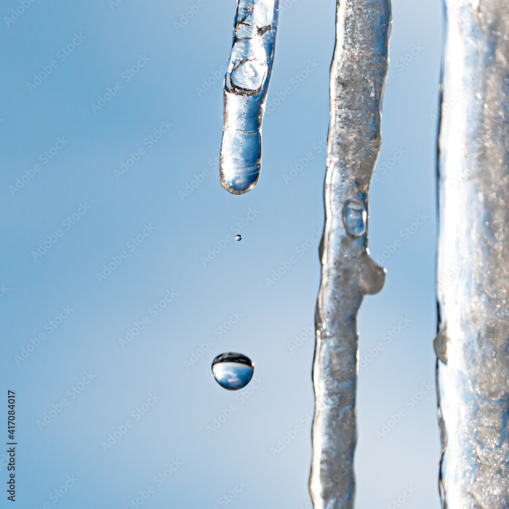 Fototapeta premium water drop from icicle with sky on background