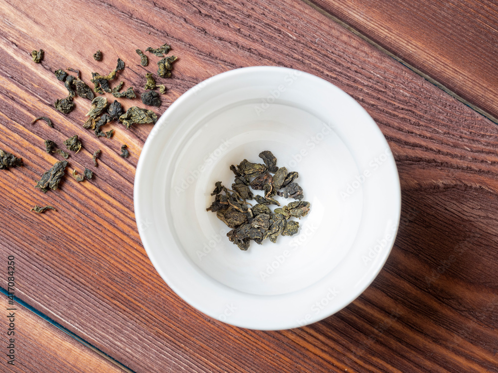 dry Chinese tea is poured into a white bowl before cooking. Wooden background, top view, flat lay. Healthy and delicious drink dry Chinese tea is poured into a white bowl before cooking. Wooden background, top view, flat lay. Healthy and delicious drink