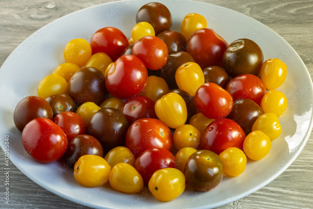 Multicolored tomatoes of different varieties in a dish. Fashionable vegan food. Multicolored tomatoes of different varieties in a dish. Fashionable vegan food.