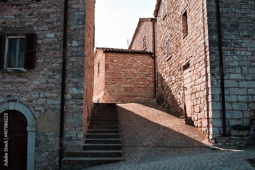 Light filters through the brick houses of a small medieval Italian village (Pesaro, Italy, Europe)