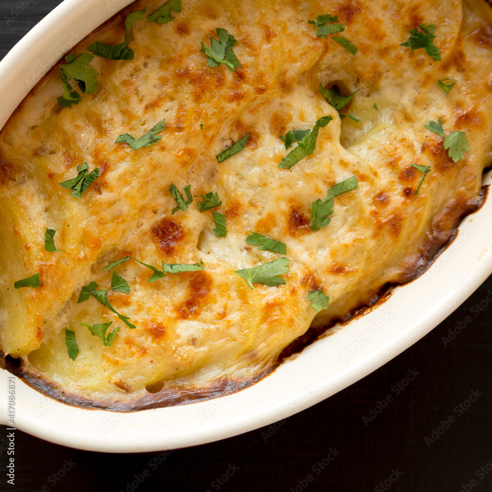 Homemade Scalloped Potatoes on a black background, top view. Flat lay, overhead, from above. Close-up. Homemade Scalloped Potatoes on a black background, top view. Flat lay, overhead, from above. Close-up.