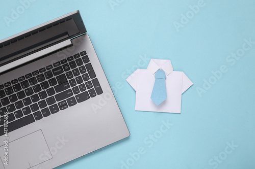 Origami paper shirt with tie and laptop on blue background. Business concept, online work