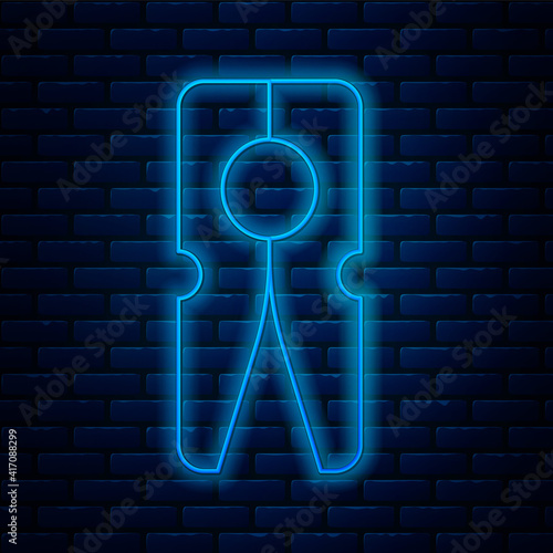 Glowing neon line Old wood clothes pin icon isolated on brick wall background. Clothes peg. Vector.
