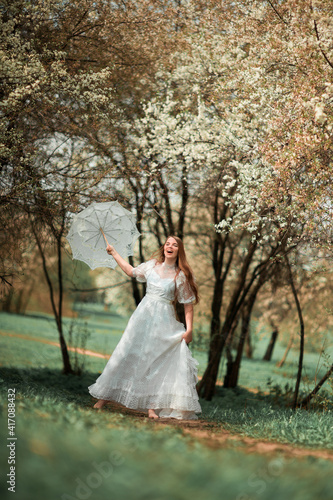 A girl in a park in a white dress and with an umbrella © allaeliseeva