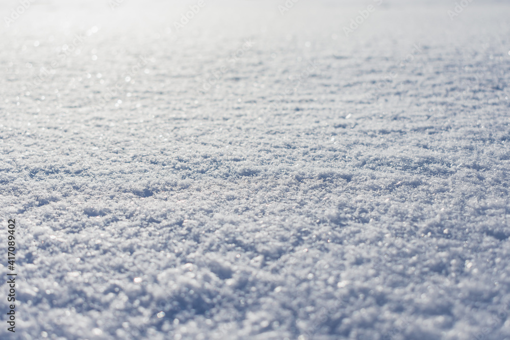 Snowy surface, the surface covered with a dense layer of snow in winter in the rays of the sun Snowy surface, the surface covered with a dense layer of snow in winter in the rays of the sun