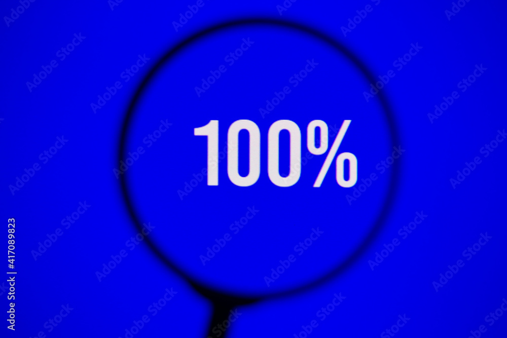 Inscription 100% on blue screen of the monitor through magnifying glass Inscription 100% on blue screen of the monitor through magnifying glass