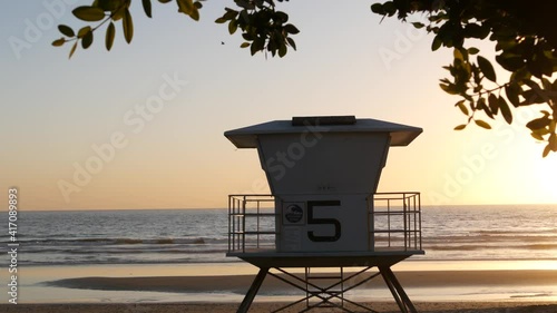 Lifeguard watch tower, sunny sunset beach, Oceanside USA. Rescue station, waterfront watchtower hut and tree leaves, pacific ocean coast atmosphere. California summertime aesthetic, Los Angeles vibes.