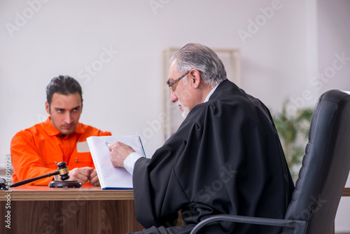Fotografi Old male judge meeting with young captive in courthouse