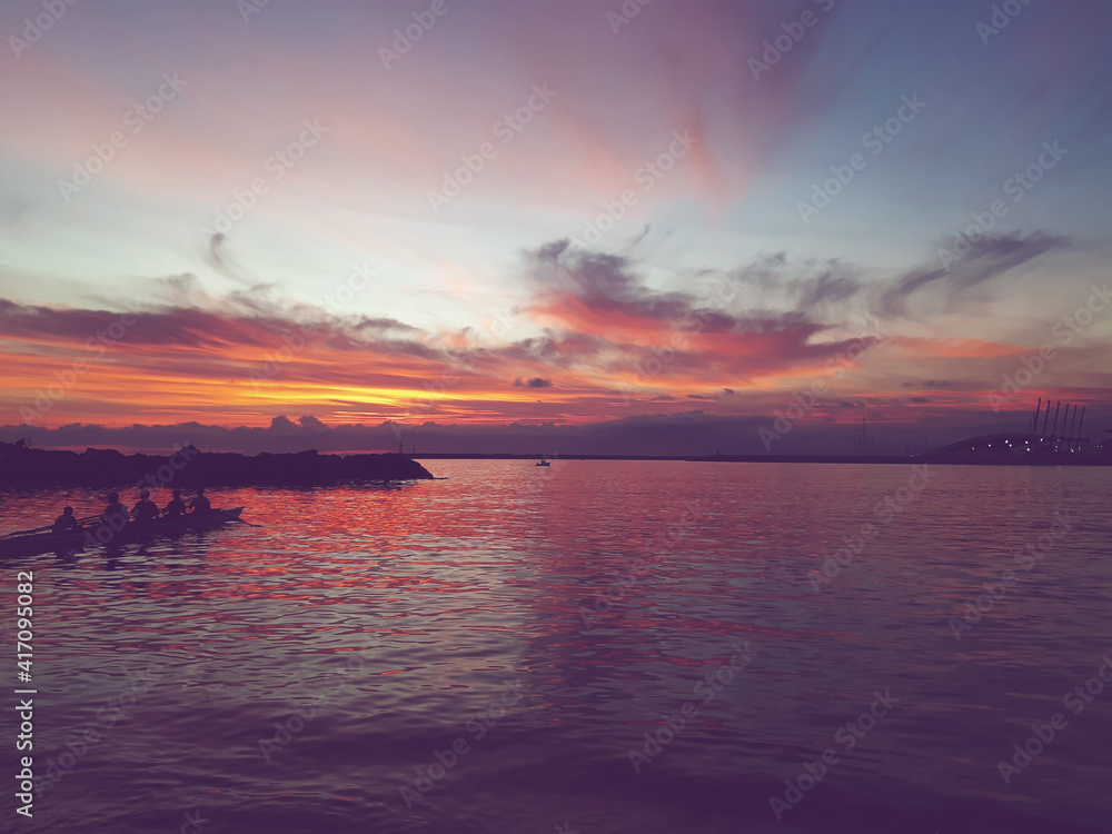 Genova, Italy - February 26, 2021: Beautiful sunset over the sea of Genova in winter days. Amazing red and orange coloured sky reflecting into the water. Genova, Italy - February 26, 2021: Beautiful sunset over the sea of Genova in winter days. Amazing red and orange coloured sky reflecting into the water.